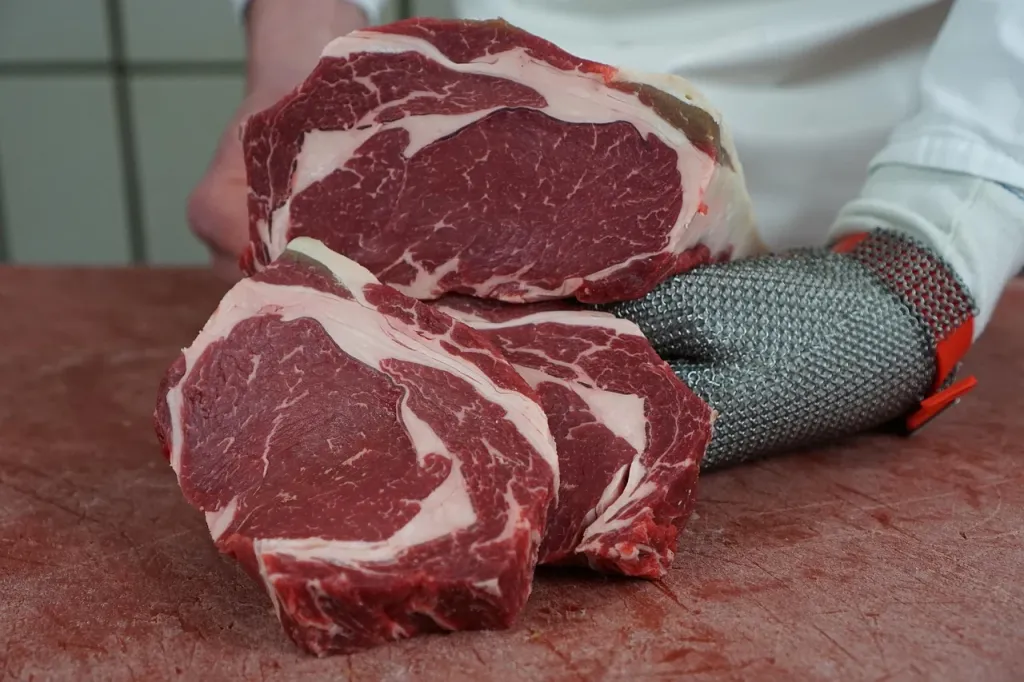Soczysty stek ribeye w glazurze sojowo-imbirowej, posypany szczypiorkiem i sezamem na ciemnym talerzu.
